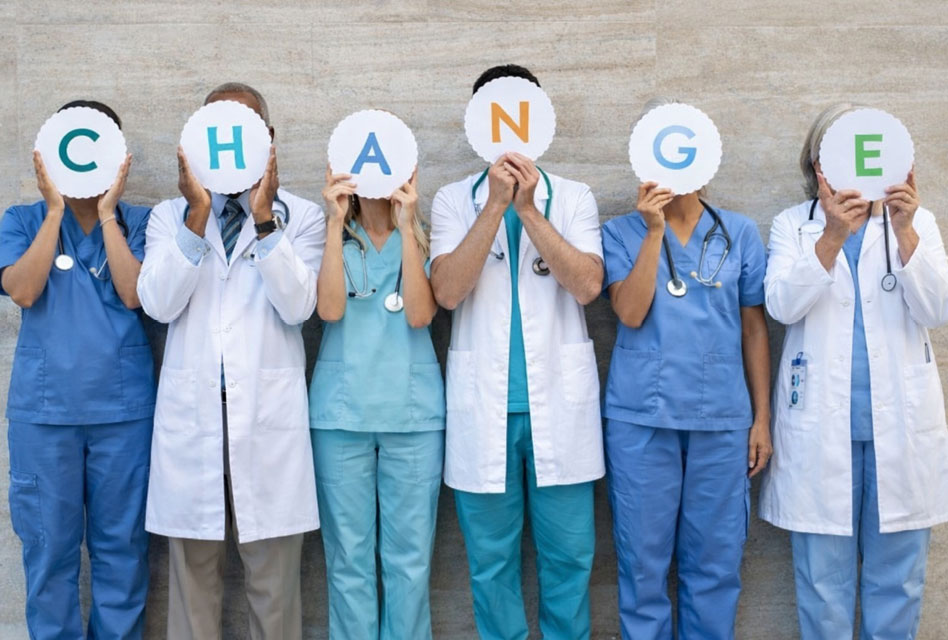 Health care workers hold up signs that spell out change
