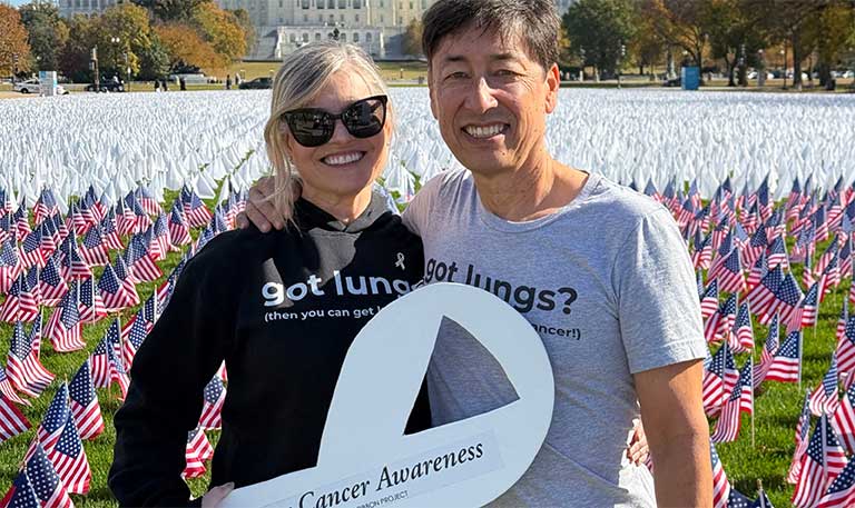 Heidi and Pierre Onda hold up a large white ribbon for lung cancer awareness.