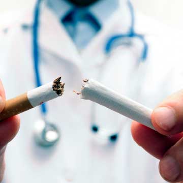 A person in a white lab coat holds a broken cigarette