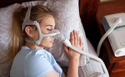A woman sleeps with a positive airway pressure machine