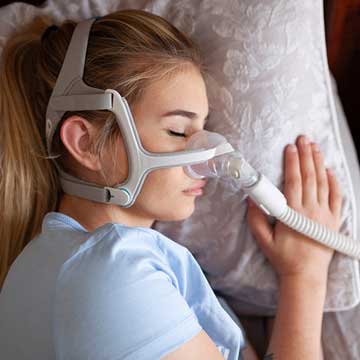 A woman sleeps with a positive airway pressure machine